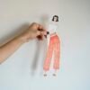 Crop anonymous female dressmaker holding cut out fashion illustration against white wall while creating new collection in light atelier