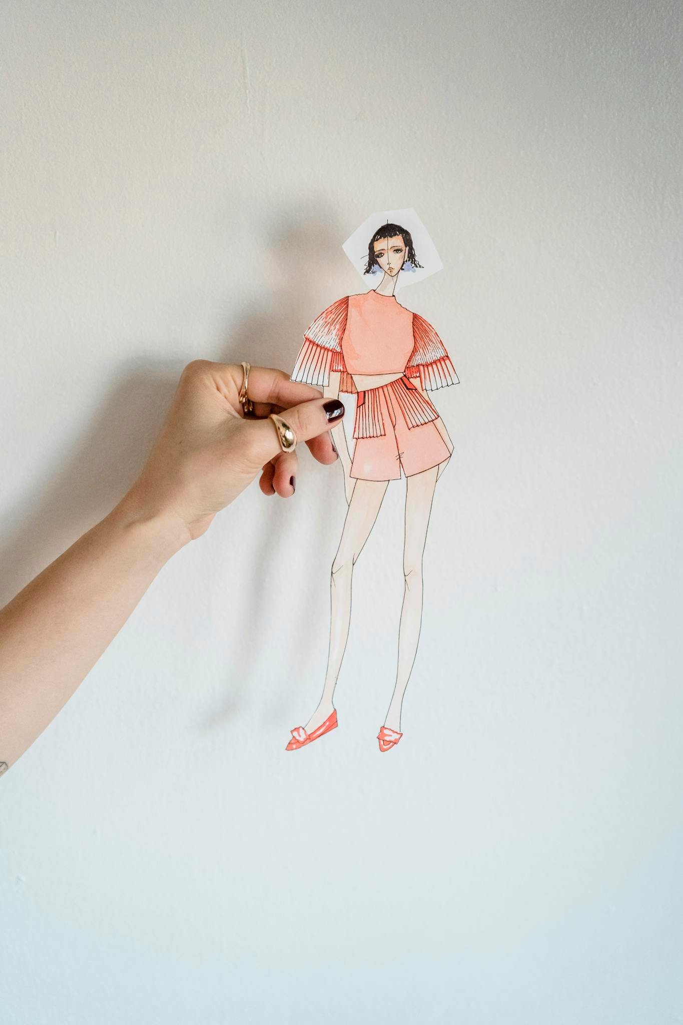 Crop faceless female tailor showing fashion paper doll in studio