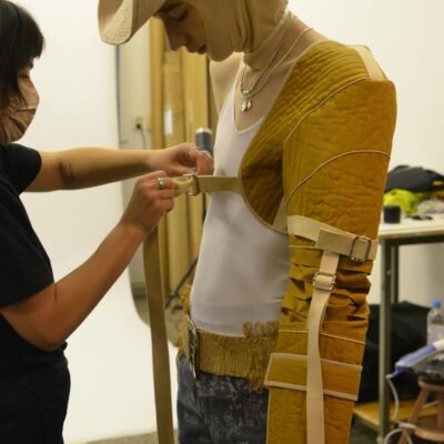 Crop female tailor measuring male model in workshop