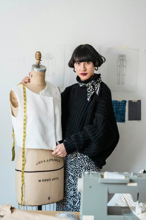 Tailor with mannequin and measuring tape in workshop